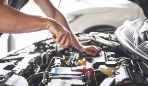 muscular-car-service-worker-repairing-vehicle
